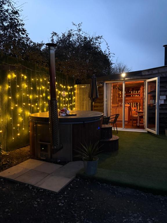 a backyard with an outdoor grill with lights on a fence at Bridie -rose rural shepherd hut , sleeps 4 with wood fuel hot tub -mini safari -on your doorstep small exotic animals in Kington