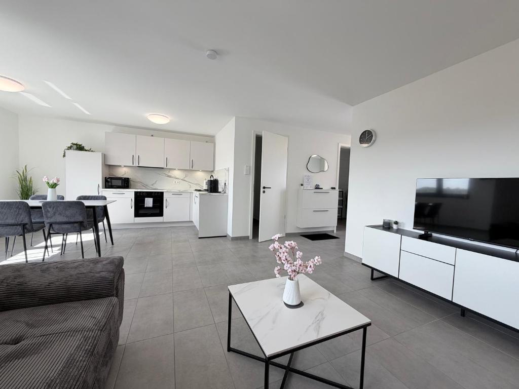 a living room with a couch and a table with flowers at BILEANCA - Neubau-Ferienwohnungen Rheinhausen Europa-Park in Rheinhausen