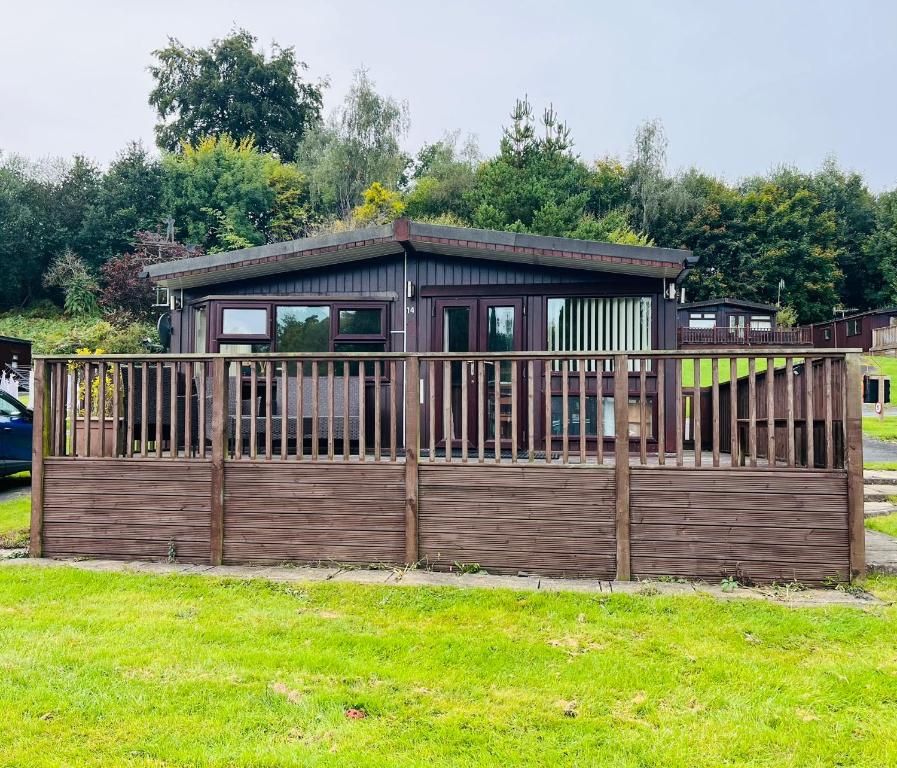 a house with a wooden fence in a yard at Afon Lodge in Maesmynis