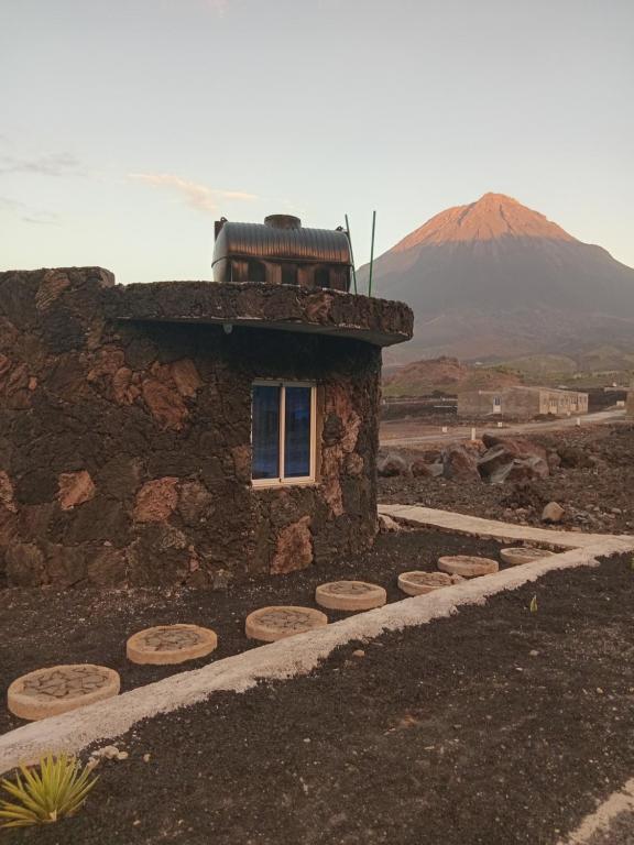 a stone building with a window and a mountain in the background at Funco Vulcao in Cova Figueira