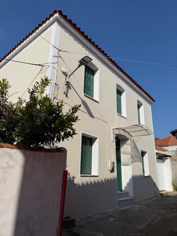 a white house with green shuttered windows at Apollon Heritage House in Palaiókipos