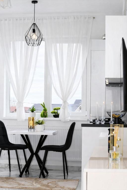 a kitchen with a white table and chairs and a window at White Pearl Residence in Roşu