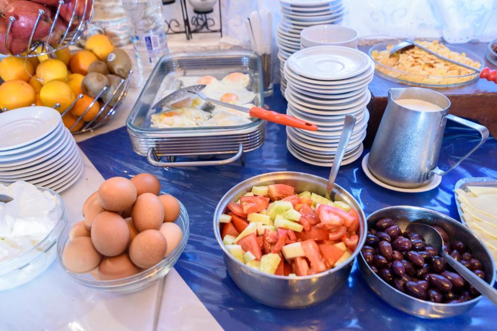 a table with bowls of fruit and plates of food at Hotel Porto Perissa in Perissa