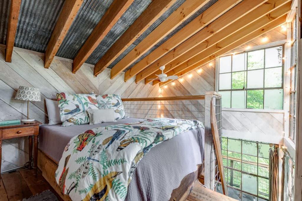 a bedroom with a bed in a room with windows at Treetop Hideaways: Luna Loft Treehouse in Flintstone