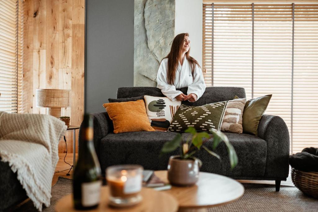 a woman sitting on a couch in a living room at Leśniczanka in Brenna