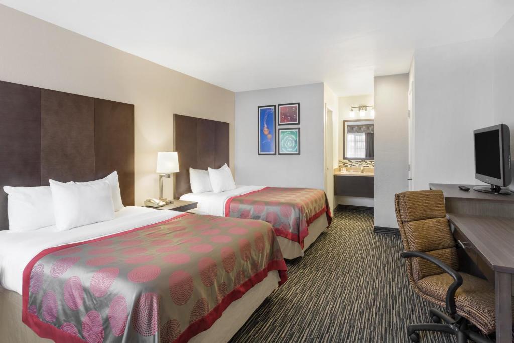 a hotel room with two beds and a desk at Ramada by Wyndham Monterey in Monterey