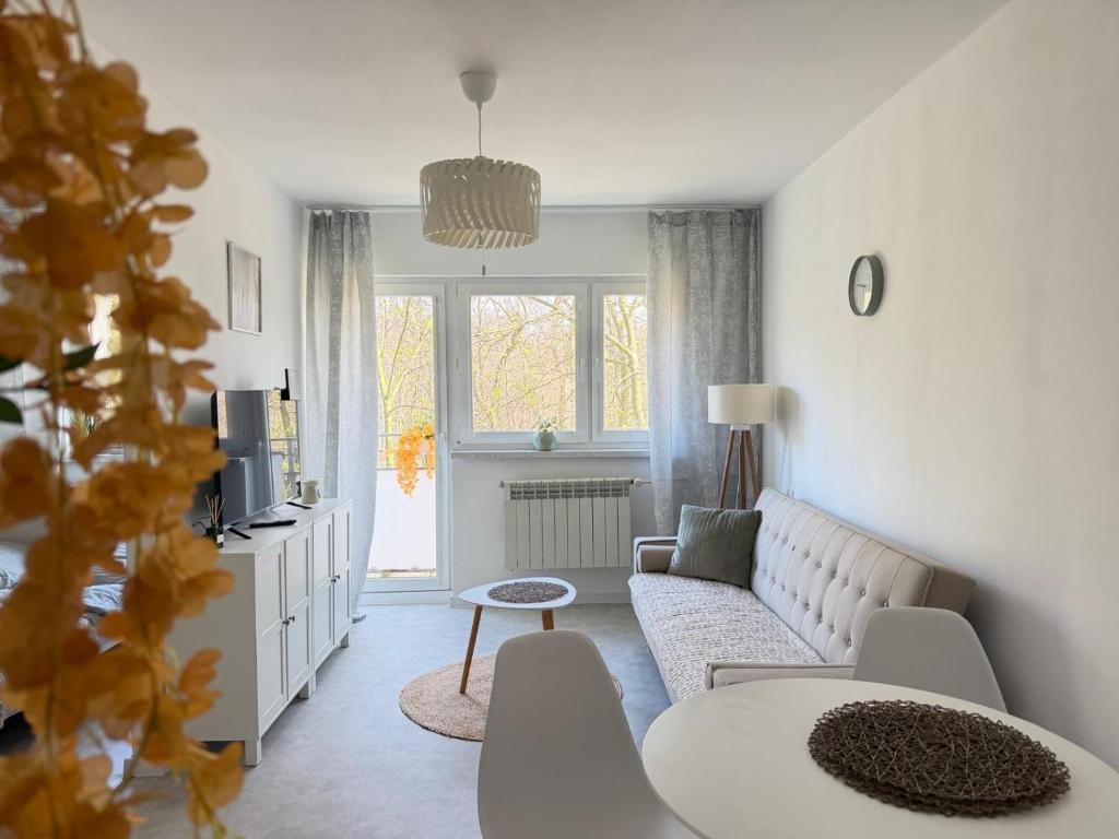a white living room with a couch and a table at Silesia Park Bytom 24H Park Miejski Centrum in Bytom