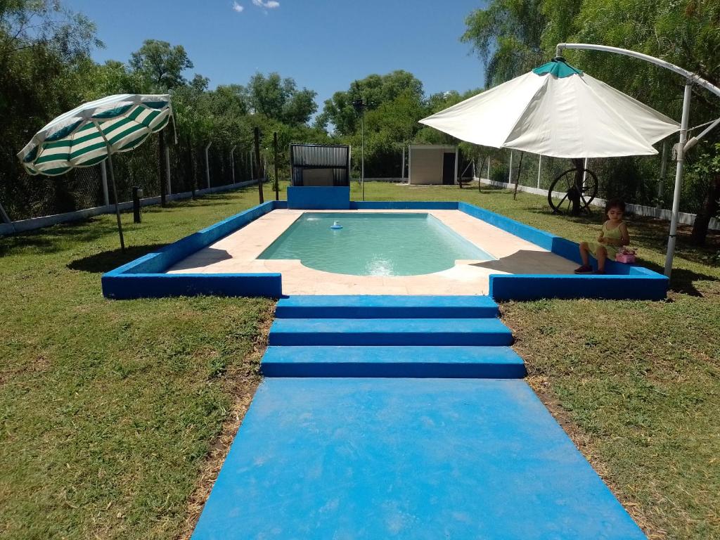 a swimming pool with blue steps and an umbrella at Aurora in Santiago del Estero