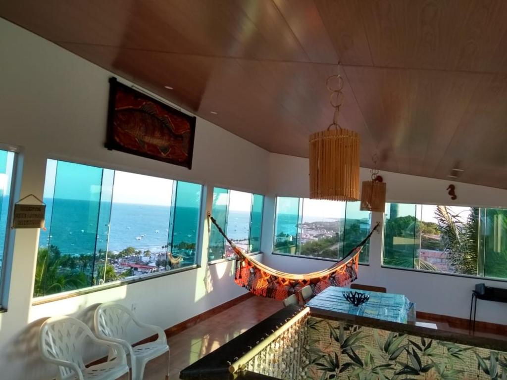 a hammock in a living room with large windows at Casa Maragogi 6 Quartos E Piscina in Maragogi