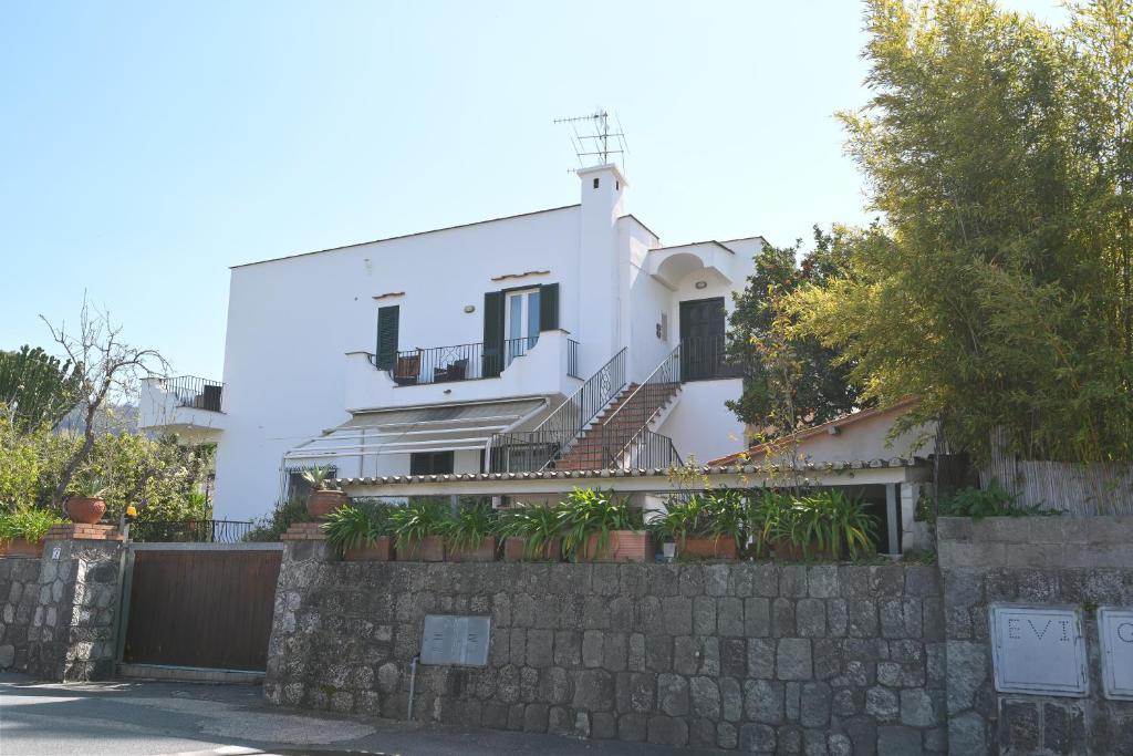 a white house with a stone wall at Don Giorgio Studios in Ischia Town