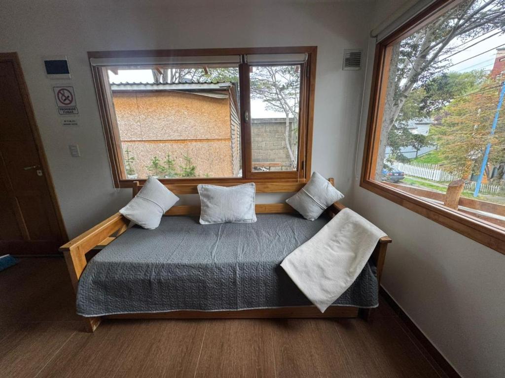 a small bedroom with a bed and a window at Las raíces departamentos in Ushuaia