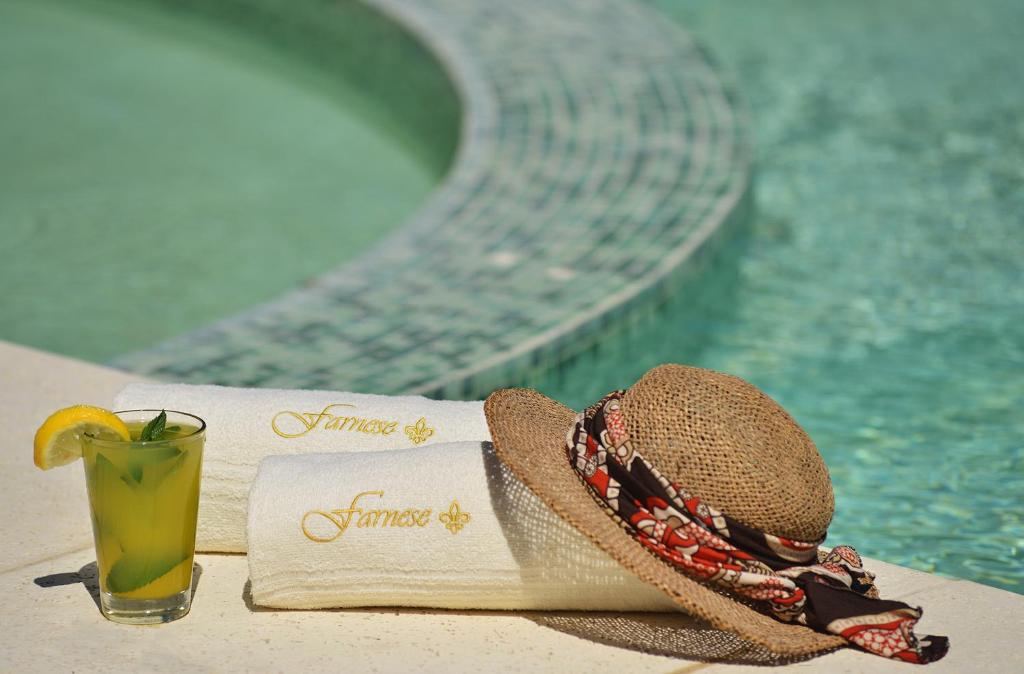a straw hat and a drink on a table next to a pool at Farnese Apart & Spa - Farnese Apart Mar in Mar de las Pampas