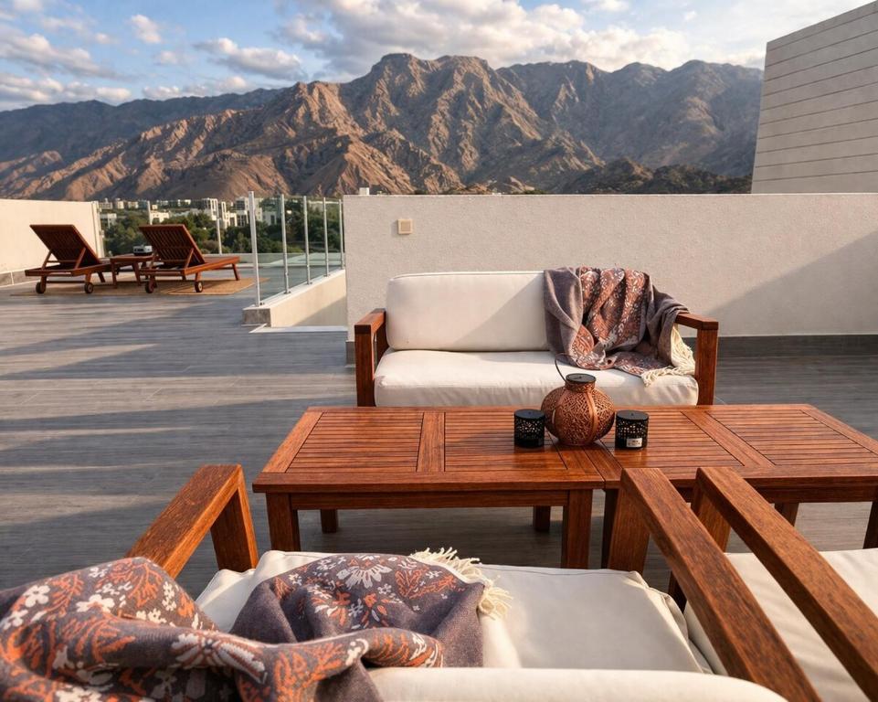 a patio with a table and chairs and mountains at Manzar View - Private Rooftop Dining & Epic Views in As Sīfah