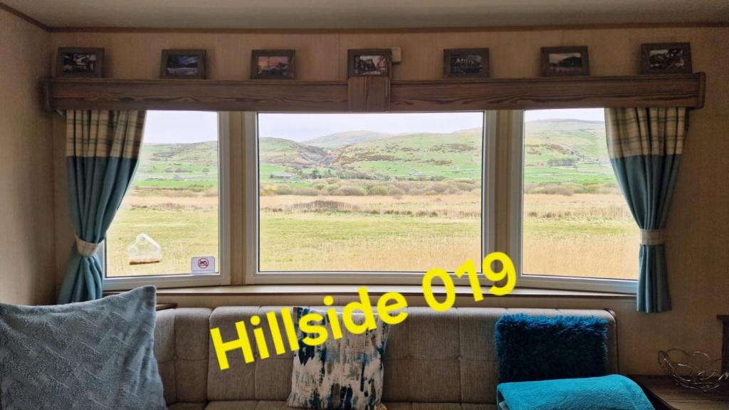 a living room with a large window with a view of a field at Lyons Sunnysands - Hillside 019 in Barmouth