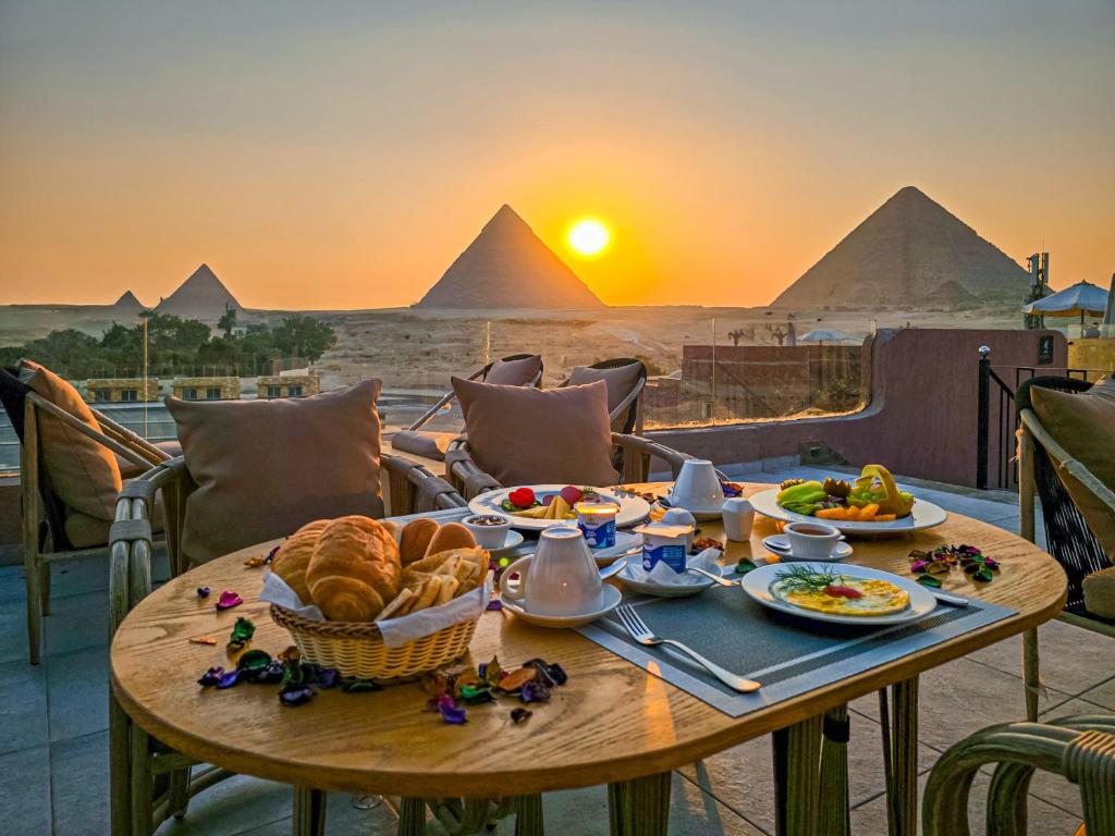 a table with food and a view of the pyramids at LE Pacha BoutiQue Hotel in Cairo