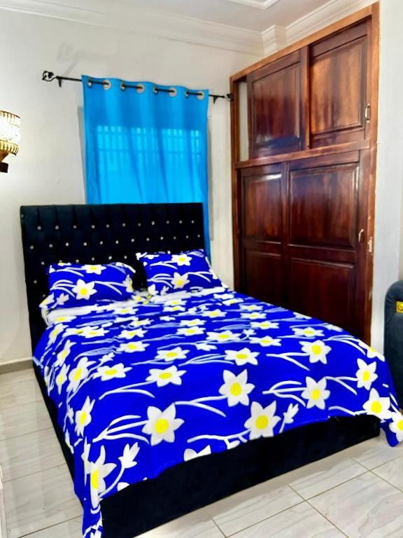 a bedroom with a blue bed with white flowers at NT Dreamhouse Cameroon in Zalom