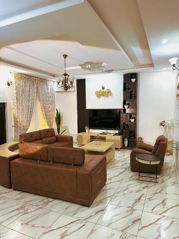 a living room with two brown couches and a flat screen tv at Bold 3 Bedroom Apartments in Abuja