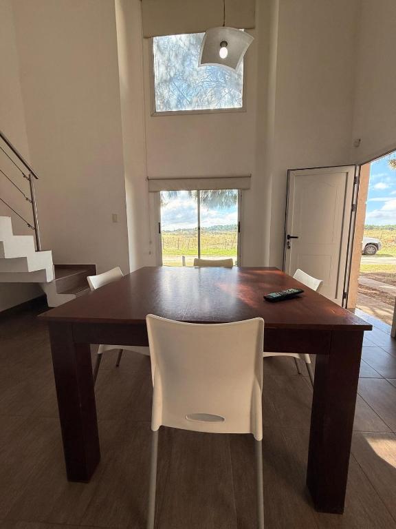 a dining room table with white chairs and a window at Cabaña Fiorella in Santa Teresita