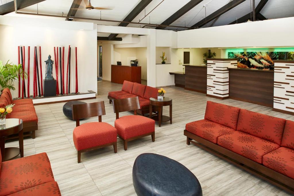 a waiting room with red chairs and tables and a lobby at Pagoda Hotel in Honolulu
