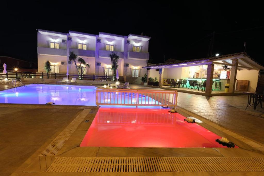 a swimming pool at night with a building in the background at Sidari Vibes Aparthotel in Sidari