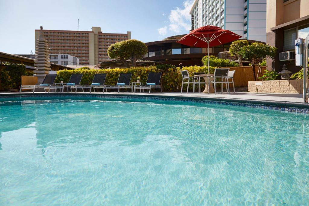 a large swimming pool with chairs and an umbrella at Pagoda Hotel in Honolulu