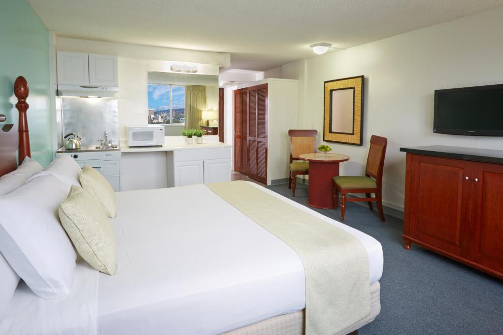 a bedroom with a large white bed and a kitchen at Pagoda Hotel in Honolulu