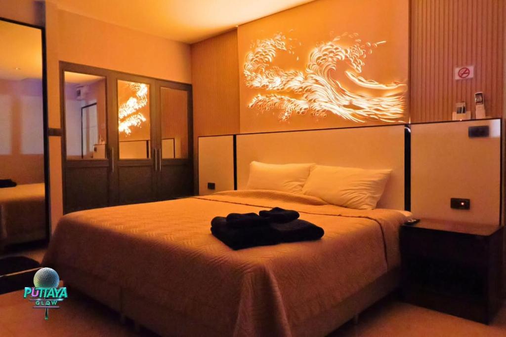 a bedroom with a bed with a painting on the wall at Puttaya Glow in Pattaya