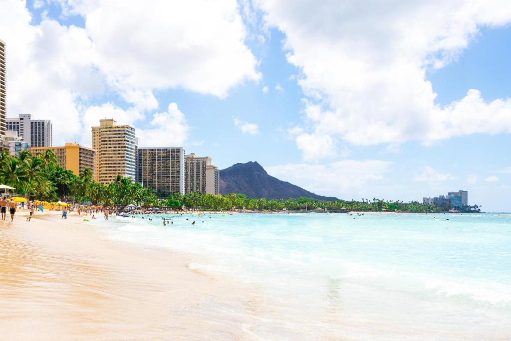 a beach with people in the water and buildings at Pagoda Hotel in Honolulu
