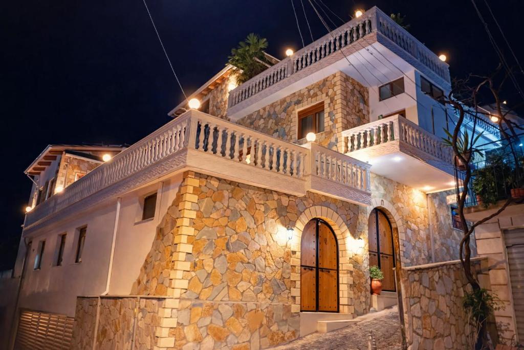 a large white building with a balcony and lights at Guest house Memushi in Gjirokastër