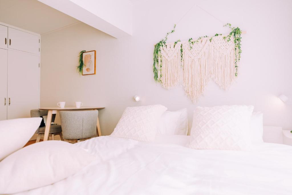 a white bedroom with a bed and a table at Chic Nakasu Apartment Perfect for 2 Guests in Fukuoka
