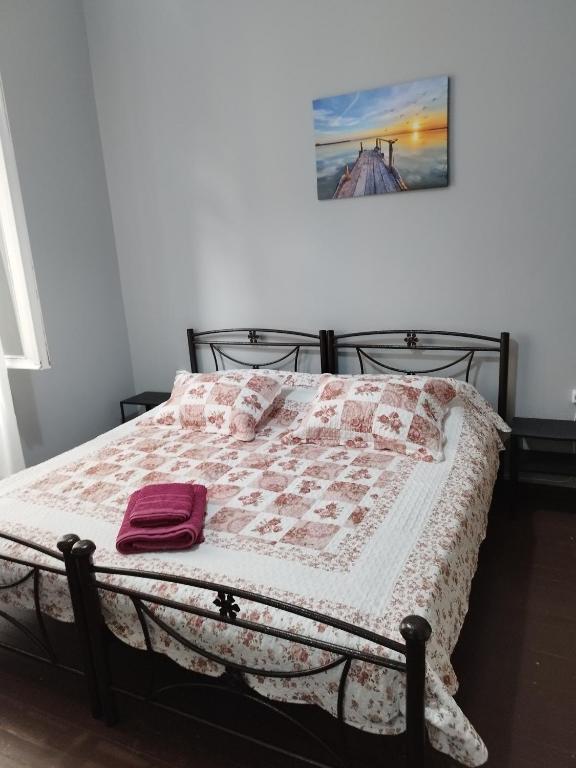 a bed with a pink and white quilt on it at comfortable room and shared kitchen and bathroom in Athens