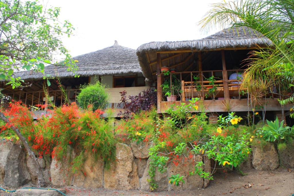 a house with a thatch roof and a bunch of flowers at Muyuyo Lodge in Ayangue