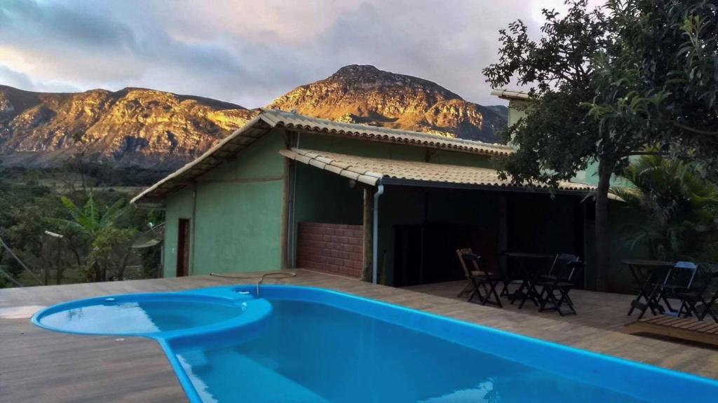 a house with a pool and mountains in the background at Pousada Lapralapa in Santana do Riacho