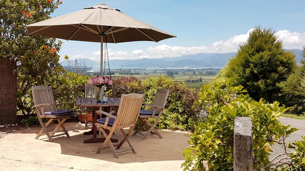 - une table et des chaises avec un parasol sur la terrasse dans l'établissement Golden Hills Farm Cottage, à Nelson