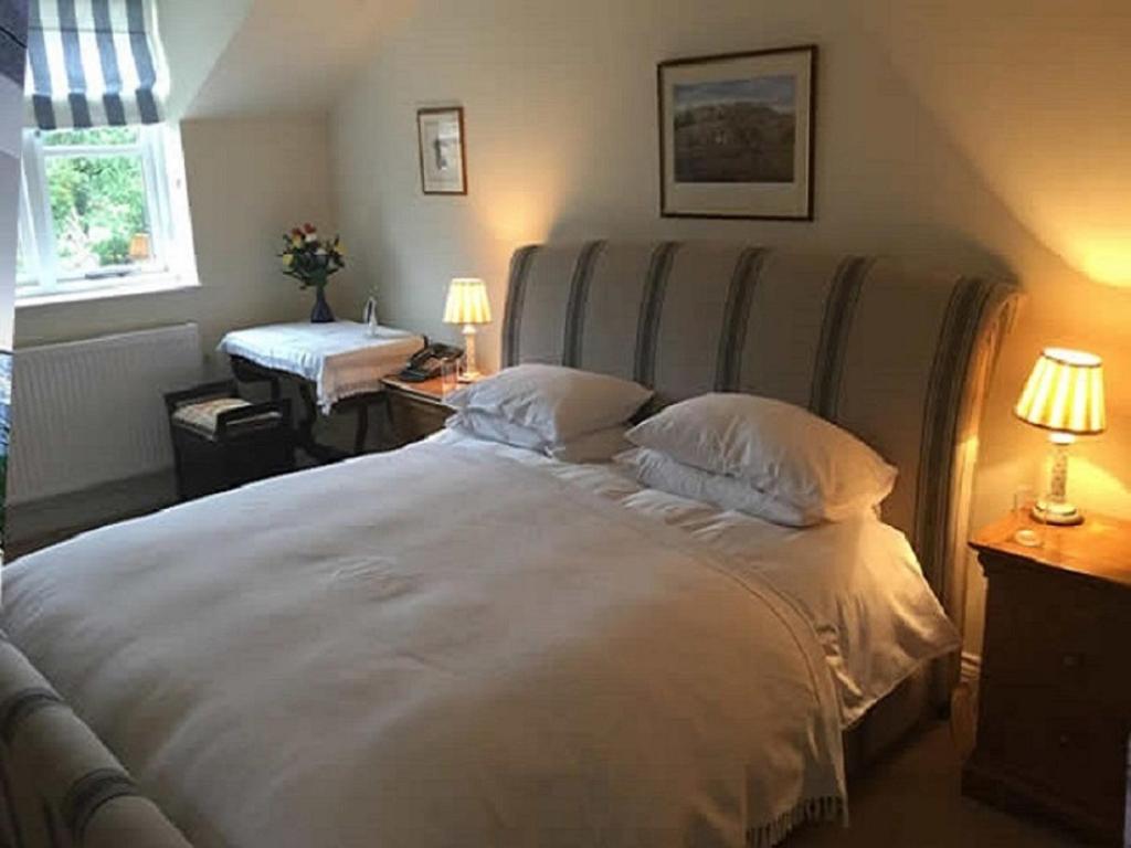 a bedroom with a large white bed with two pillows at Mill Cottage in Malpas