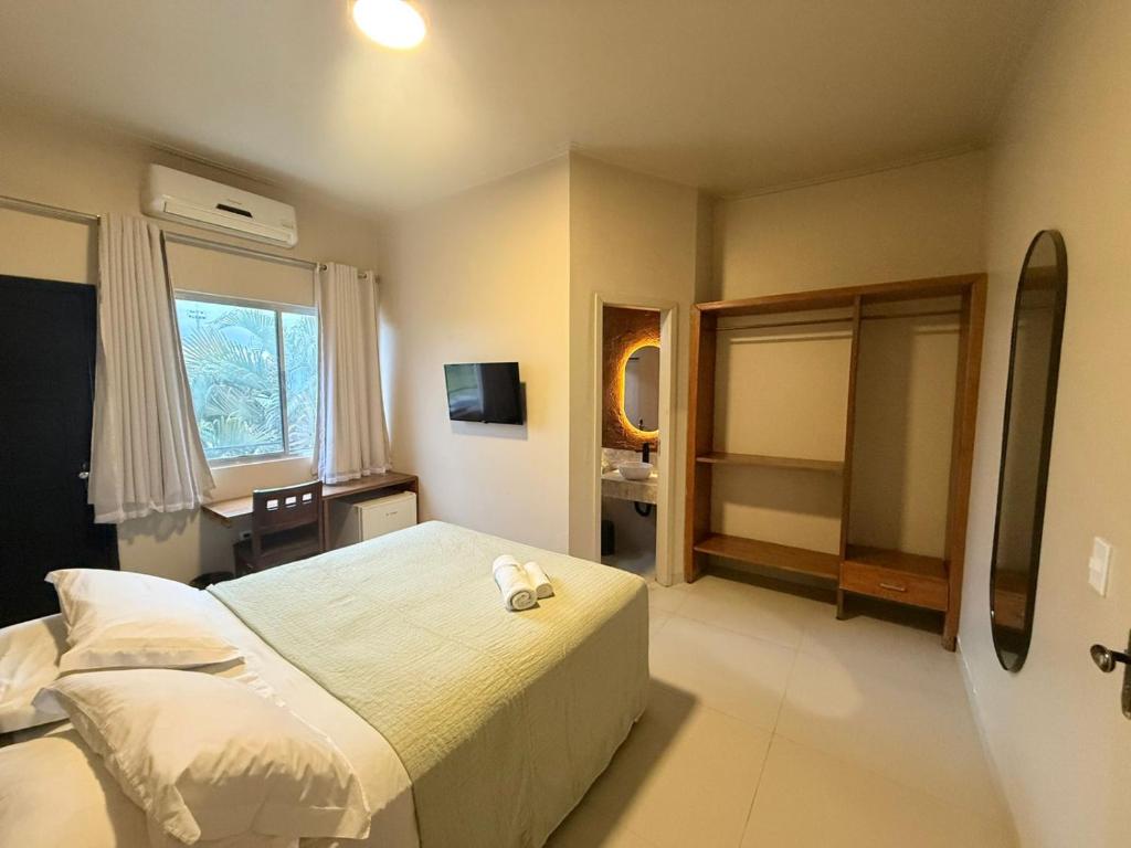 a bedroom with a bed and a desk in it at Pumma Hotel Ourilândia in Ourilândia do Norte