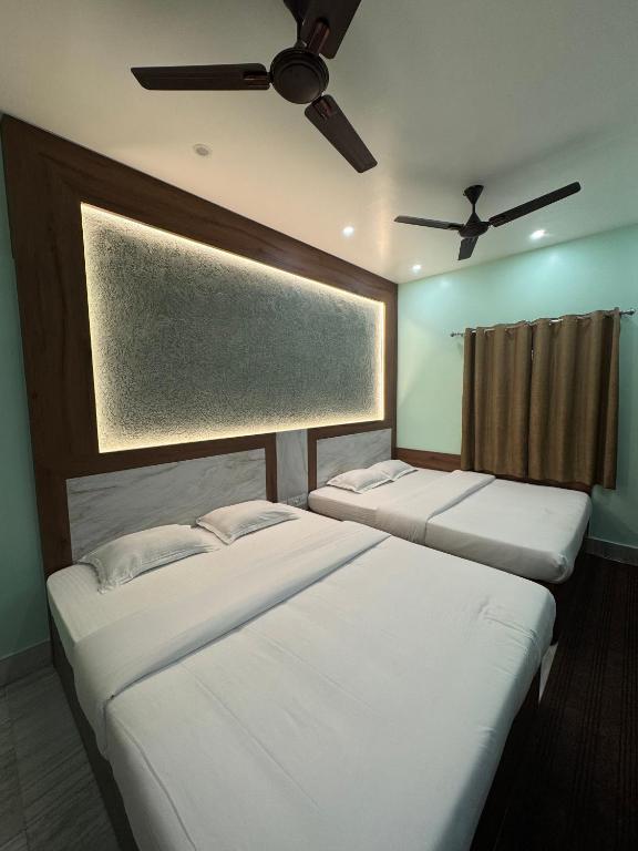 two beds in a room with a ceiling fan at HOTEL SREE DURGA in Kolkata