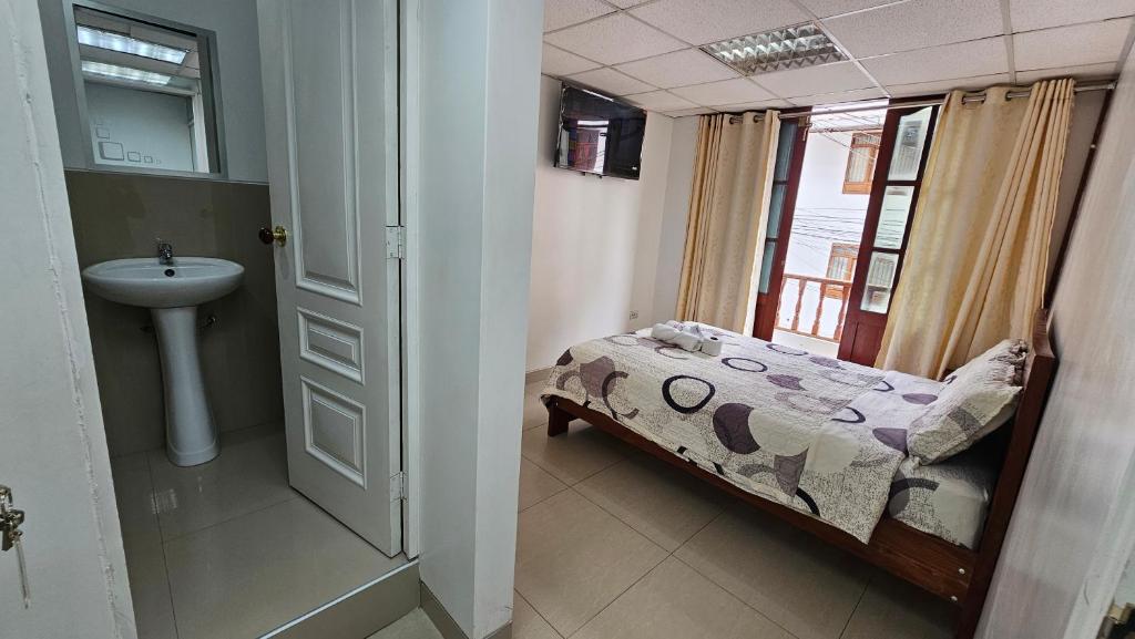 ein Badezimmer mit Bett, Waschbecken und Fenster in der Unterkunft Hostal Ticlio in Cajamarca
