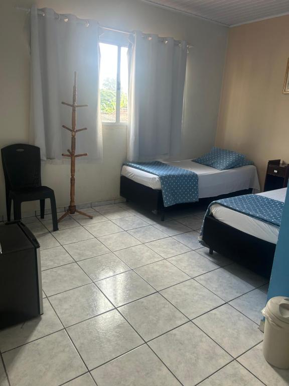 a room with two beds and a window at pousada irmãs in Pindamonhangaba