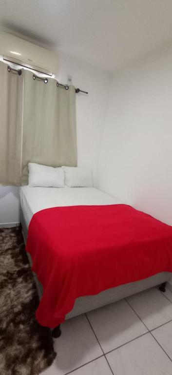 a bedroom with a red blanket on a bed at Bozena Beach Stay in Itacaré