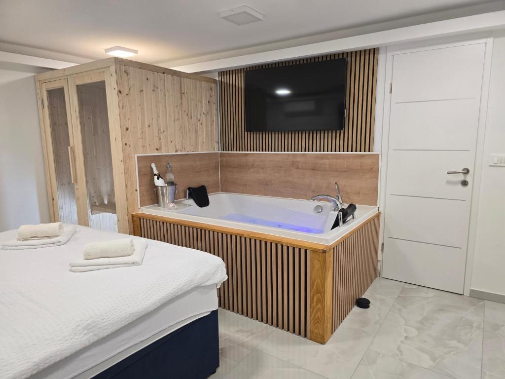 a bathroom with a tub and a tv on the wall at Jacuzzi & Sauna Edy room - city center in Zagreb