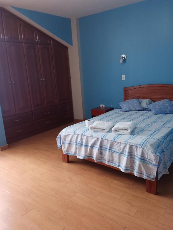 a bedroom with a bed with blue walls and wooden cabinets at Casa familiar D'Greta in San Ramón