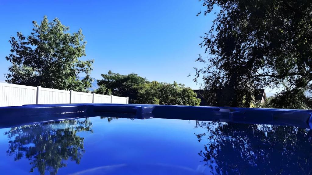 a blue swimming pool with a fence and trees at Lighthouse Basement Guest Suite in Provo