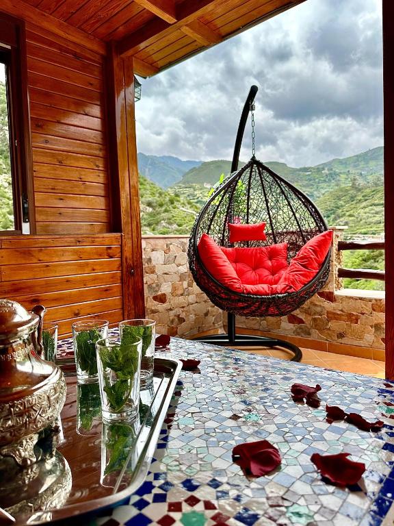 a swing chair on a porch with a table at Hotel nabil in Akchour