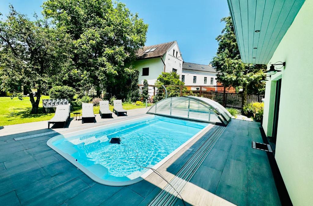 a swimming pool on a deck with chairs and a house at Chalupa pod Milesovkou in Milešov