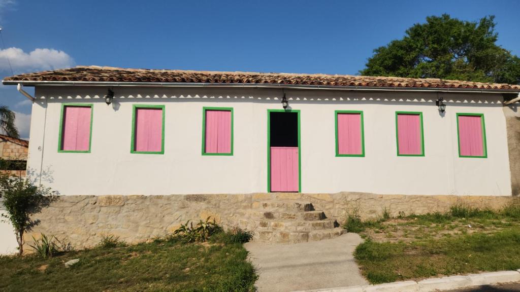 a white house with pink and green windows at Pousada Casa Matriz in Itabirito