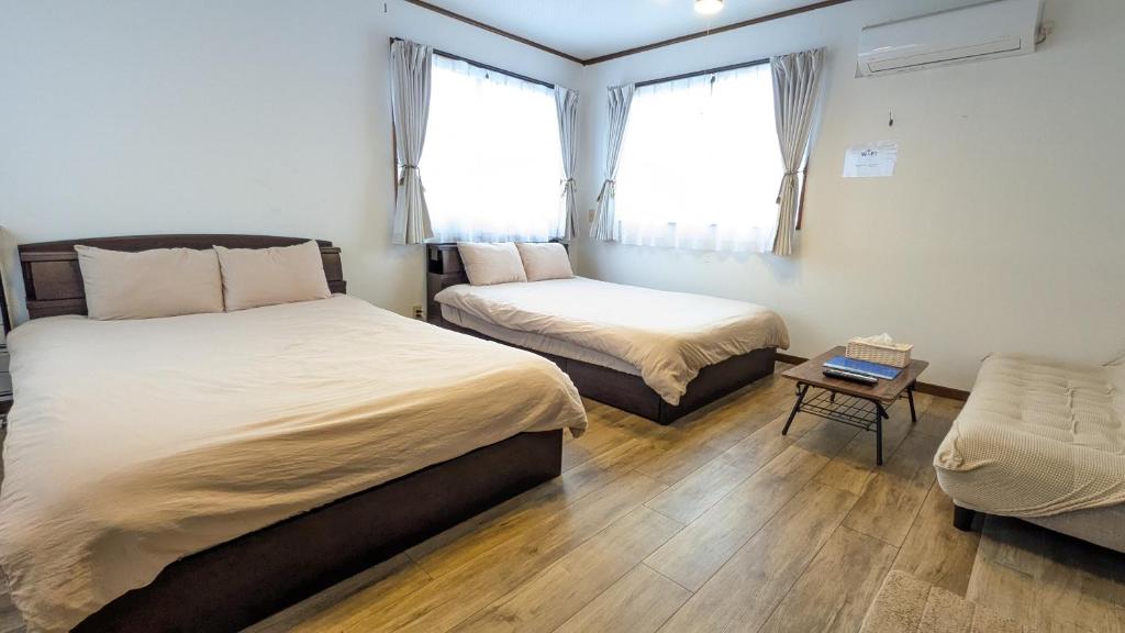 a bedroom with two beds and a chair in it at Guest House Tatara in Yasugi