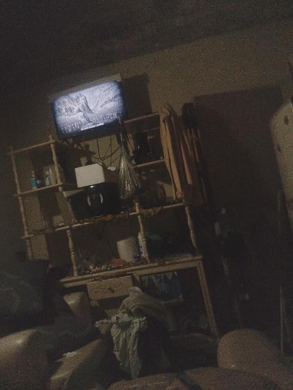 a living room with a tv in a dark room at Swallow's nest in Kingston