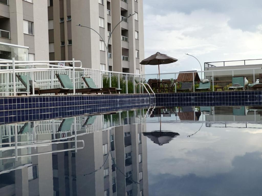 a pool with chairs and an umbrella and a building at Canto da Mantiqueira - Staffy House Extrema in Extrema