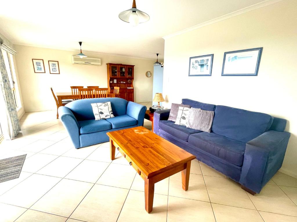 a living room with two blue couches and a coffee table at Bay-Ann Cottage in Kingscote